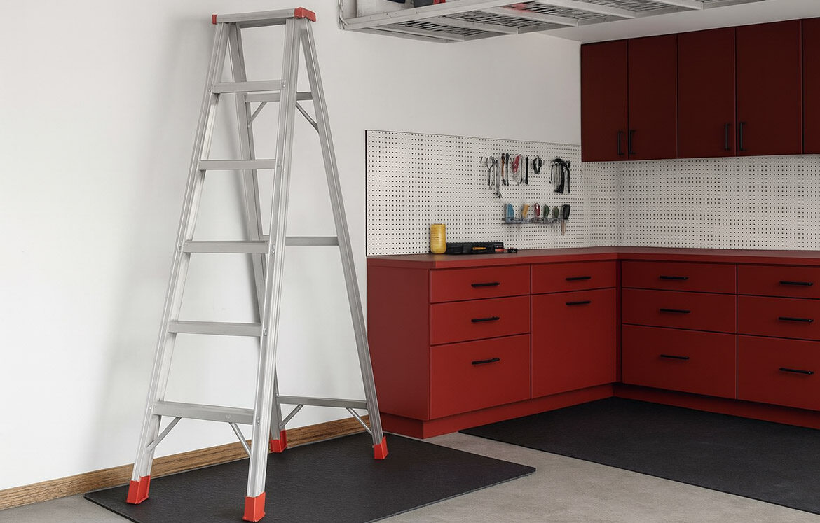 Samostoječa aluminijasta lestev pravilno postavljena v domači delavnici kot primer varne uporabe lestve na stabilni podlagi.